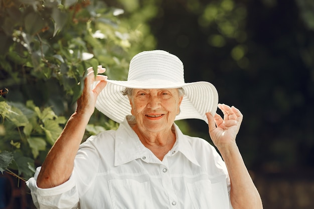 Retrato de hermosa mujer de edad en el parque. Abuela con sombrero blanco.