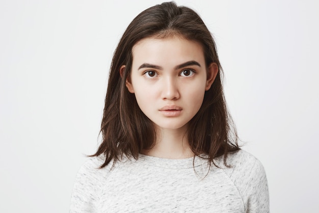 Retrato de hermosa mujer europea con cabello castaño corto, mirando con expresión concentrada