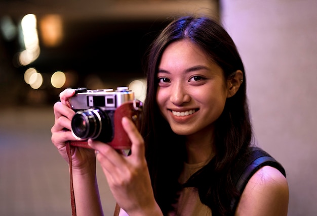 Foto gratuita retrato de hermosa mujer fotógrafa en la ciudad por la noche