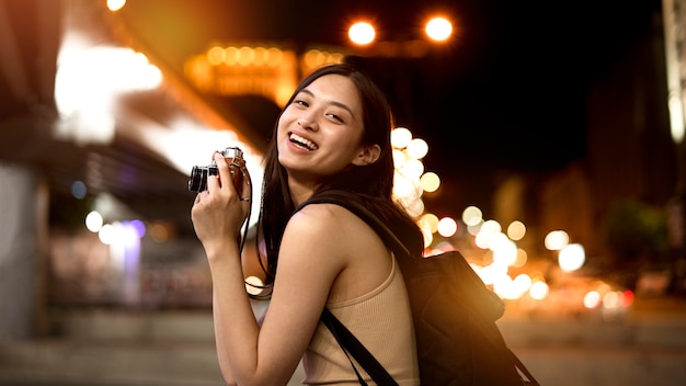 Foto gratuita retrato de hermosa mujer fotógrafa en la ciudad por la noche