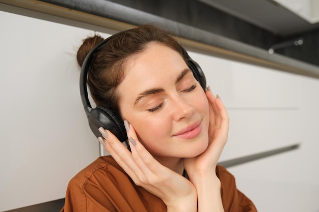 Foto gratuita retrato de una hermosa mujer joven con auriculares relajándose cierra los ojos de placer escuchando