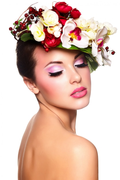 Retrato de hermosa mujer joven con estilo con coloridas flores en la cabeza.