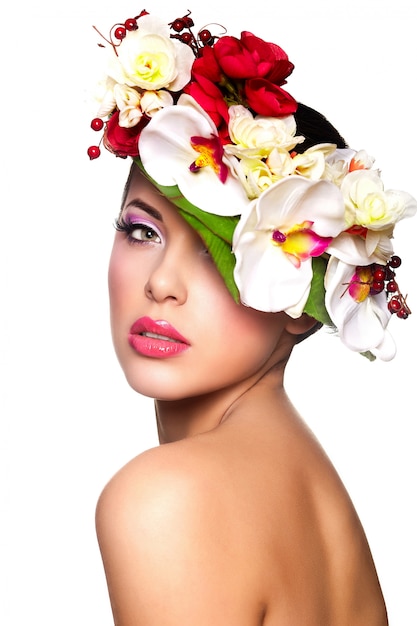 Retrato de hermosa mujer joven con estilo con coloridas flores en la cabeza.