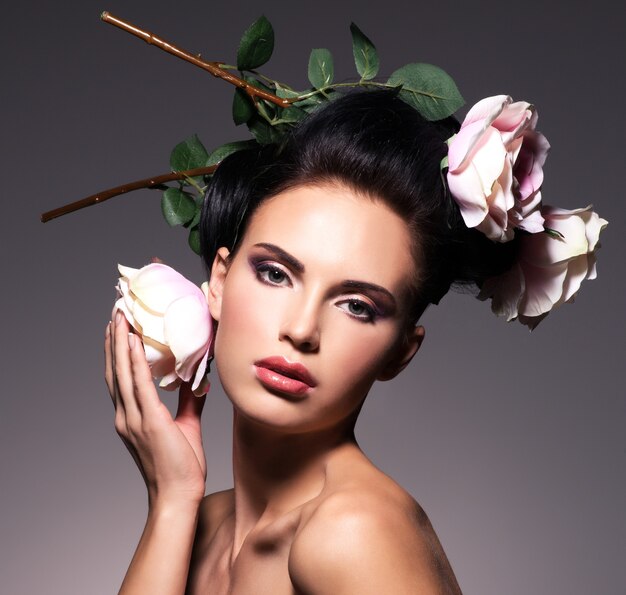 Retrato de hermosa mujer joven con flores en poses de cabello