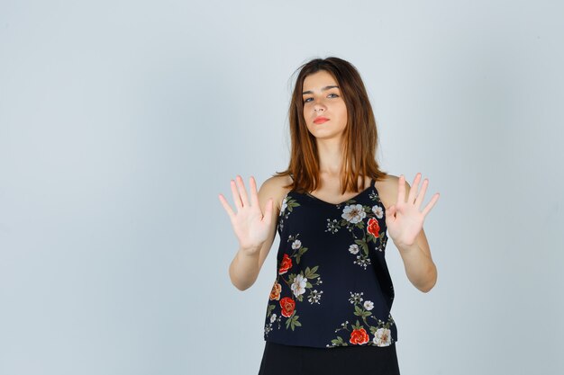 Retrato de hermosa mujer joven mostrando gesto de parada en blusa