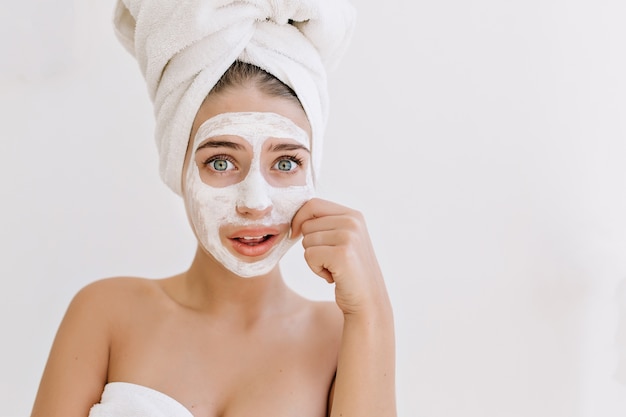 Retrato de hermosa mujer joven con toallas después de tomar un baño hacer máscara cosmética y se preocupa por su piel.