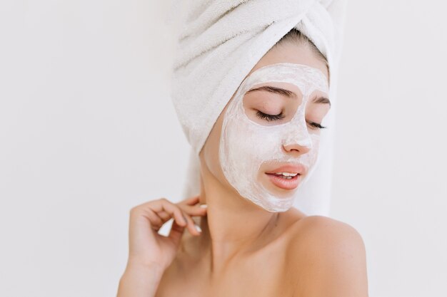 Retrato de hermosa mujer joven con toallas después de tomar el baño hacer mascarilla cosmética en su rostro.