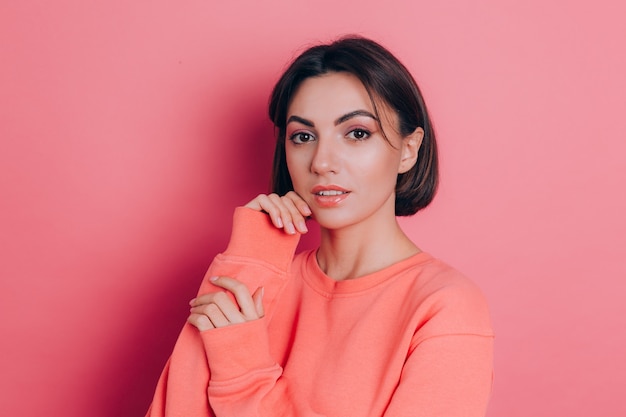 Retrato de hermosa mujer morena linda sonriente modelo en ropa casual suéter melocotón con maquillaje brillante y labios rosados aislados