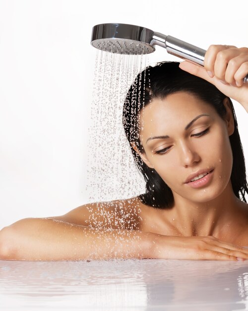 Retrato de una hermosa mujer morena tiene ducha en manos con agua que cae