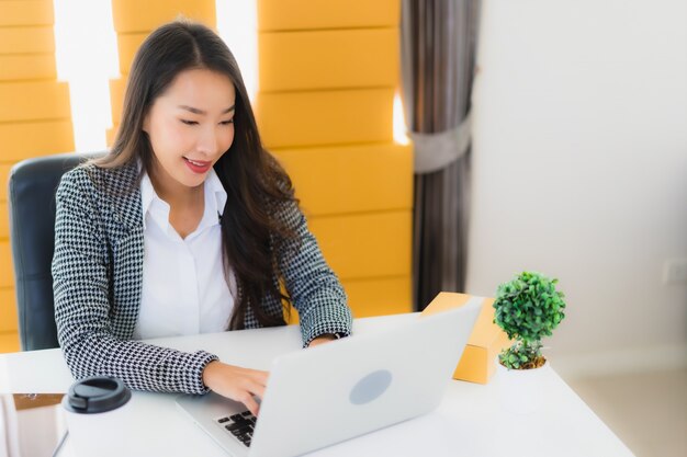 Retrato hermosa mujer de negocios asiática joven trabajar desde casa con teléfono móvil portátil con caja de cartón lista para enviar