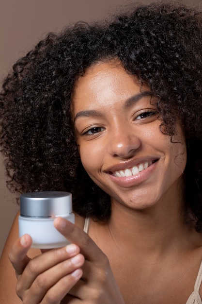 Retrato de hermosa mujer negra sosteniendo una crema para la piel