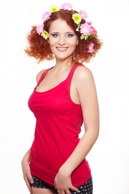 Retrato de hermosa mujer pelirroja jengibre sonriente en tela roja con flores de colores rosa amarillas en cabello aislado en blanco