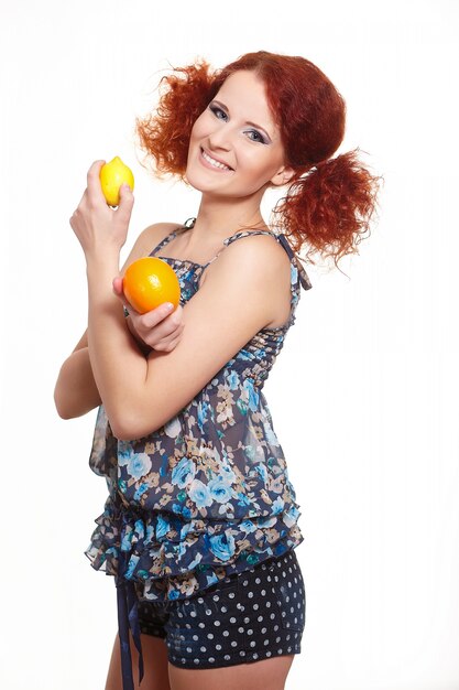 Foto gratuita retrato de hermosa mujer pelirroja jengibre sonriente en vestido de verano aislado en blanco con naranja y limón