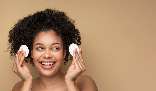 Retrato de una hermosa mujer quitando su maquillaje con almohadillas