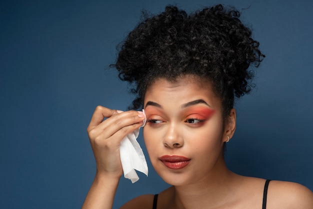 Retrato de una hermosa mujer quitando su maquillaje con un pañuelo desmaquillador