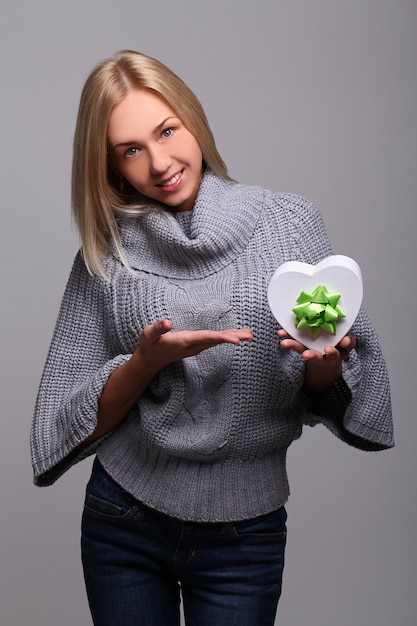 Retrato de hermosa mujer rubia con caja de regalo en forma de corazón