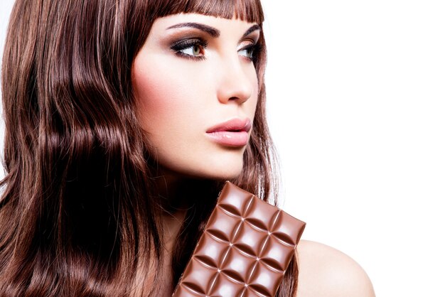 Retrato de hermosa mujer sexy con barra de chocolate - aislado en blanco.