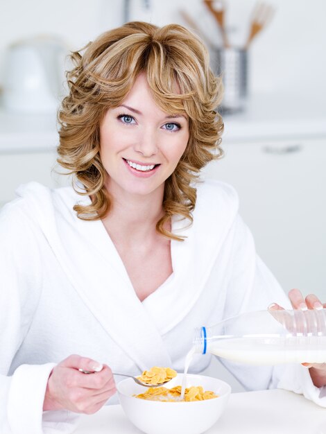 Retrato de hermosa mujer sonriente feliz comiendo copos de maíz en el kithcen