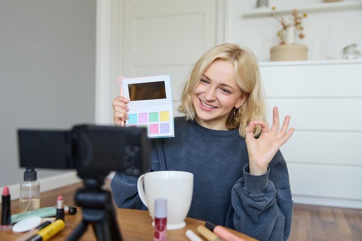 Foto gratuito retrato de una hermosa mujer sonriente grabando un video en su habitación tiene la cámara en la mesa de café revisando