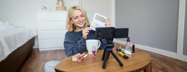 Foto gratuito retrato de una hermosa mujer sonriente grabando un video en su habitación tiene la cámara en la mesa de café revisando