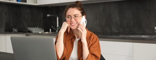 Retrato de una hermosa mujer sonriente trabajando desde casa hablando por teléfono móvil llamando a un cliente