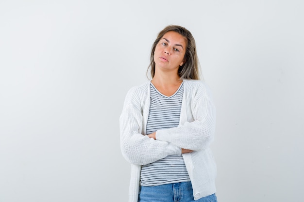 Retrato de hermosa mujer sosteniendo los brazos cruzados en la chaqueta y mirando pensativo vista frontal