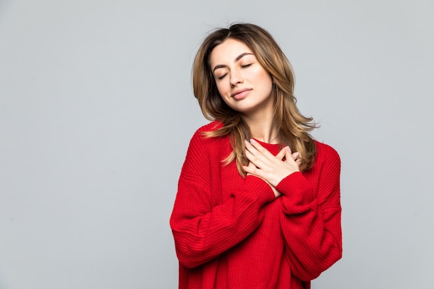 Retrato de una hermosa mujer vestida con suéter rojo aislado sobre pared gris