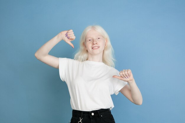 Retrato de hermosa niña albina caucásica aislada en la pared azul