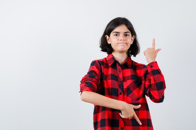 Retrato de una hermosa niña apuntando hacia arriba y hacia abajo