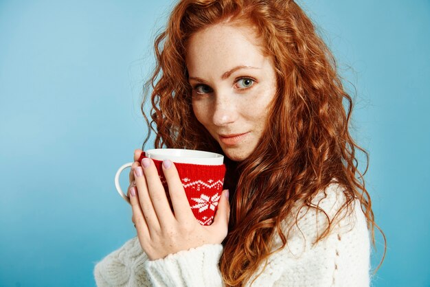 Retrato de hermosa niña bebiendo té o café caliente