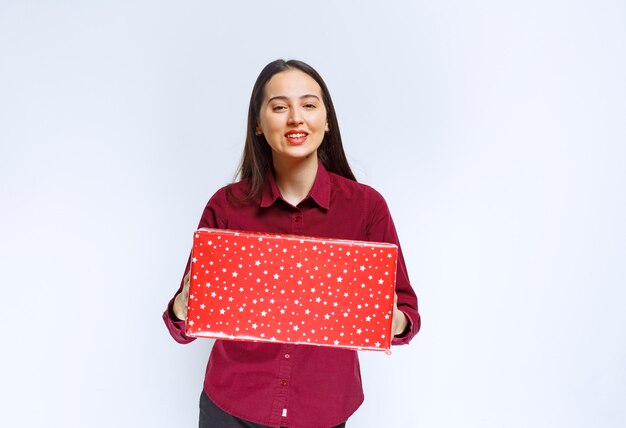 Retrato de una hermosa niña con caja actual sobre pared blanca.