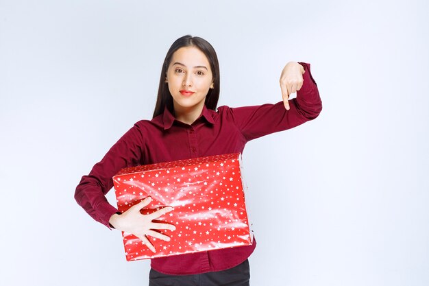 Retrato de una hermosa niña con caja actual sobre pared blanca.