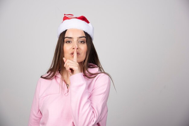 Retrato de una hermosa niña con un sombrero de año nuevo que muestra un gesto de silencio.