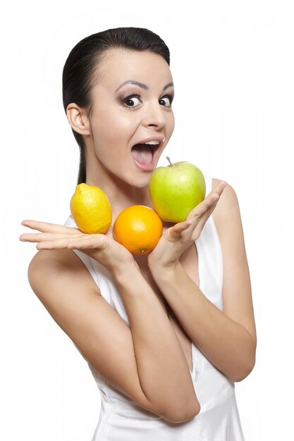 Retrato de hermosa niña sonriente feliz con frutas limón y manzana verde y naranja aislado en blanco