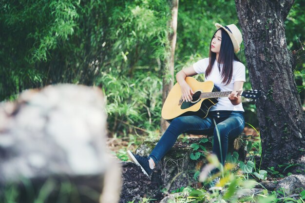 Retrato de una hermosa niña tocando la guitarra con la escritura en la naturaleza