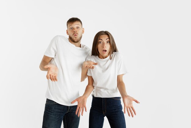 Retrato de hermosa pareja joven aislado sobre fondo blanco de estudio. Expresión facial, emociones humanas, concepto publicitario. Copyspace. La mujer y el hombre miran conmocionados, asombrados y maravillados.