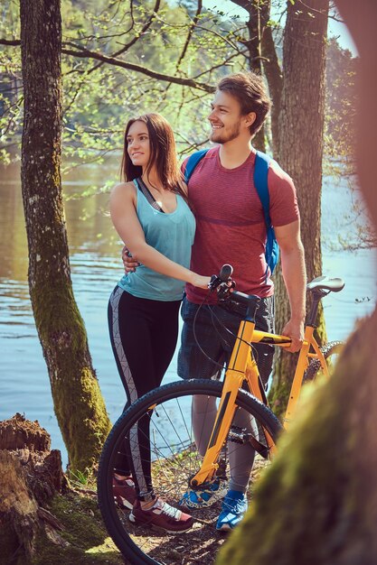 Retrato de una hermosa pareja. Pareja sonriente relajándose mientras está de pie junto al lago en el bosque.