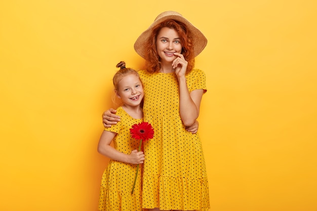 Retrato de hermosa pelirroja madre e hija posando en vestidos similares