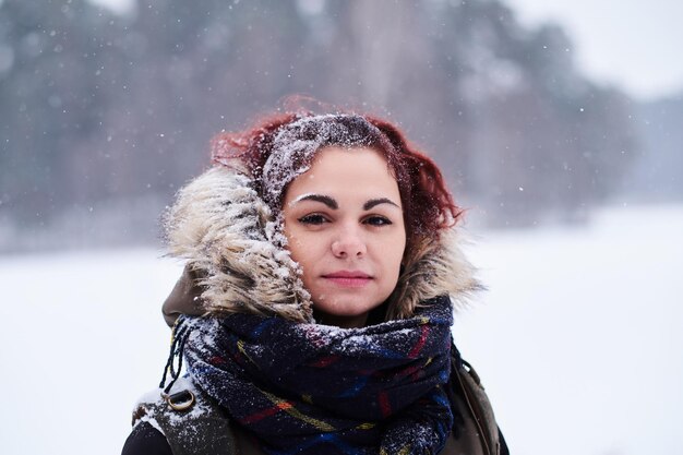 Retrato de una hermosa pelirroja con ropa de abrigo en el bosque nevado