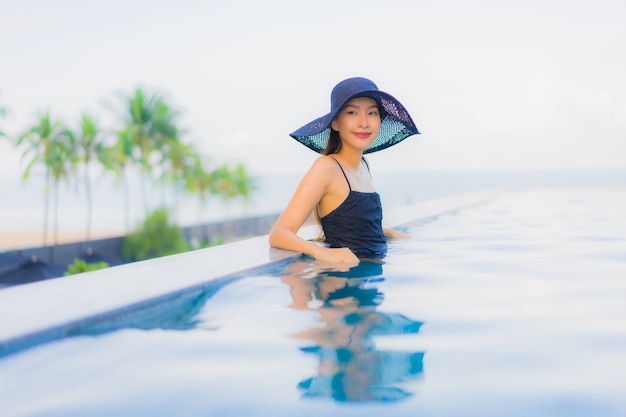 Retrato hermosas mujeres asiáticas jóvenes feliz sonrisa relajarse piscina al aire libre en el hotel