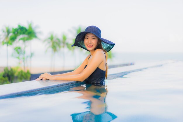 Retrato hermosas mujeres asiáticas jóvenes feliz sonrisa relajarse piscina al aire libre en el hotel