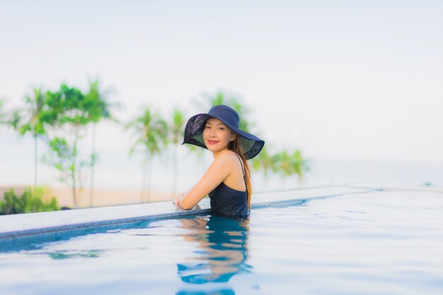 Retrato hermosas mujeres asiáticas jóvenes feliz sonrisa relajarse piscina al aire libre en el hotel