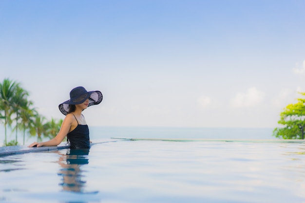 Retrato hermosas mujeres asiáticas jóvenes feliz sonrisa relajarse piscina al aire libre en el hotel