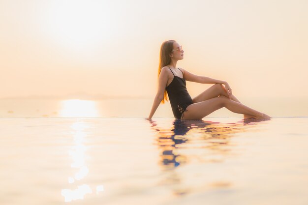 Retrato hermosas mujeres asiáticas jóvenes feliz sonrisa relajarse piscina al aire libre en el hotel