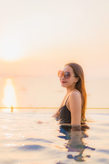 Retrato hermosas mujeres asiáticas jóvenes feliz sonrisa relajarse piscina al aire libre en el hotel