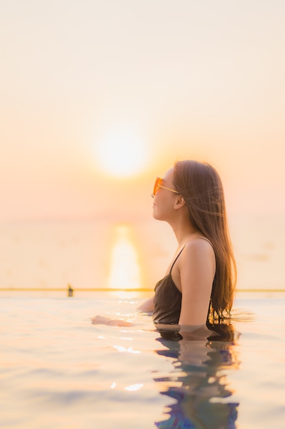 Retrato hermosas mujeres asiáticas jóvenes feliz sonrisa relajarse piscina al aire libre en el hotel