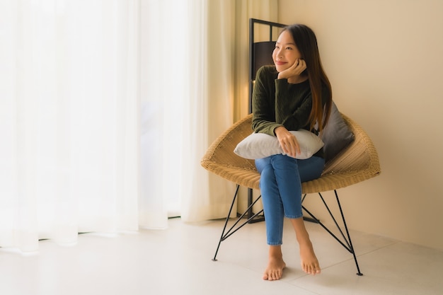 Retrato hermosas mujeres asiáticas jóvenes feliz sonrisa relajarse sentado en el sillón