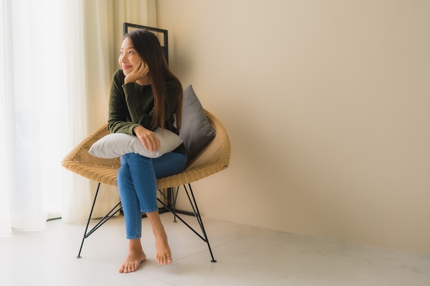 Retrato hermosas mujeres asiáticas jóvenes feliz sonrisa relajarse sentado en el sillón