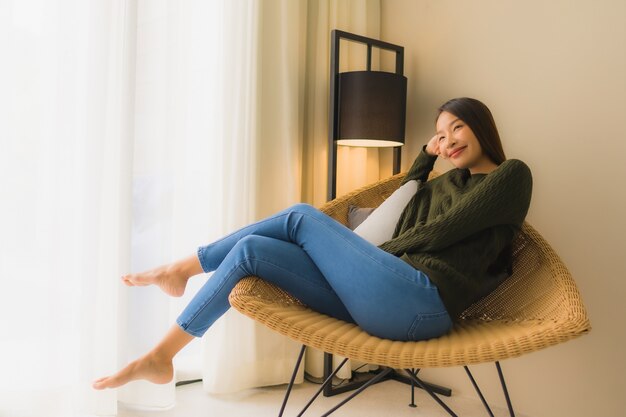 Retrato hermosas mujeres asiáticas jóvenes feliz sonrisa relajarse sentado en el sillón