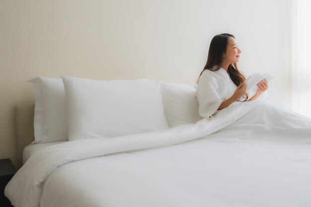 Retrato hermosas mujeres asiáticas jóvenes leen el libro en la cama